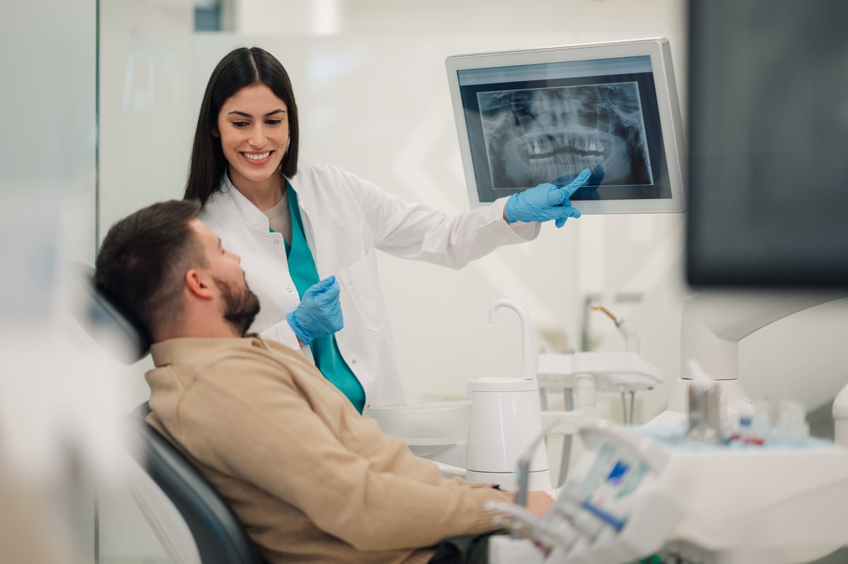 Dentista mostrando una radiografía dental a un paciente en la clínica